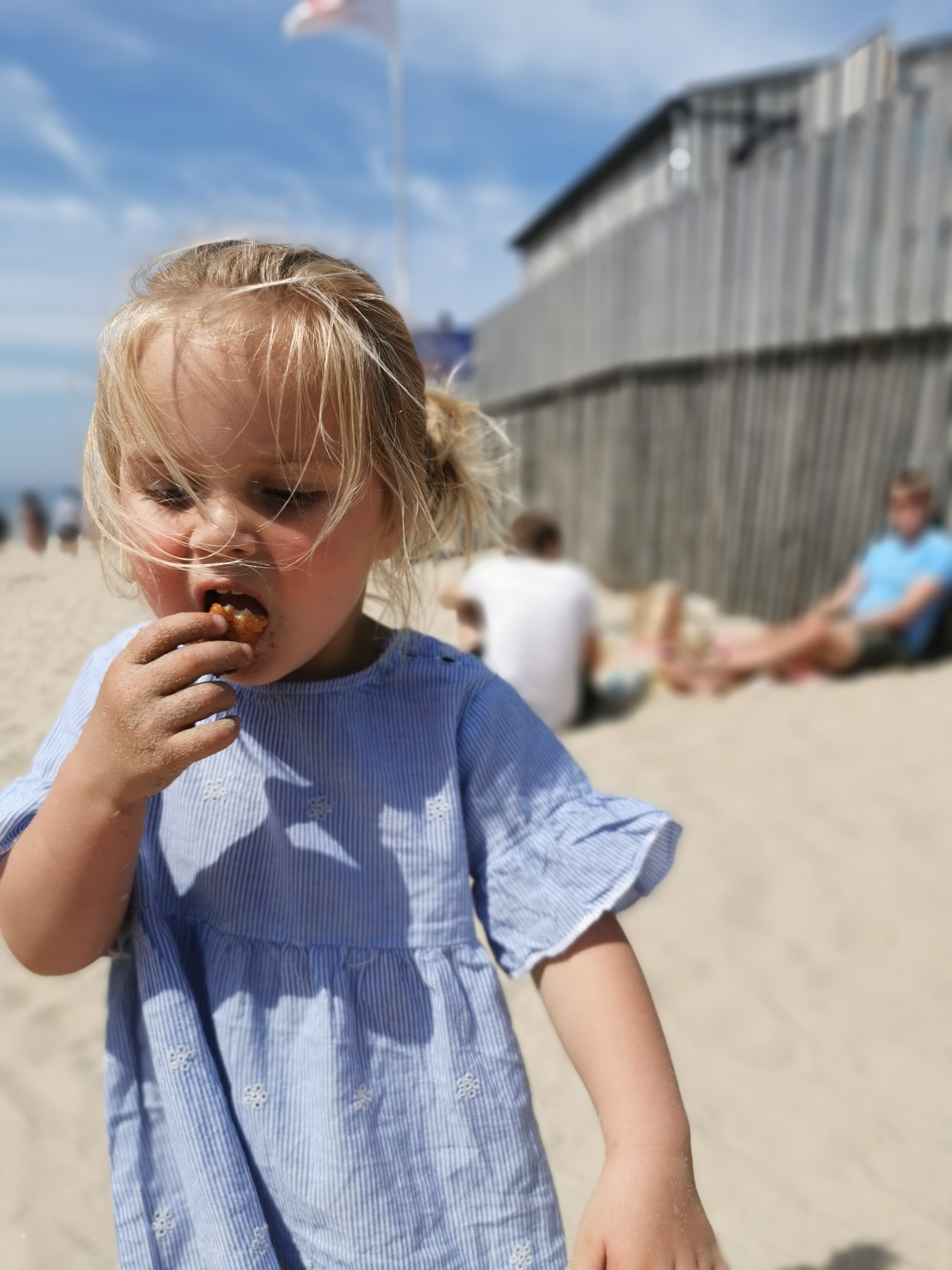 Klein meisje eet verse kibbeling op het strand bij Vis aan Zee in Egmond aan Zee